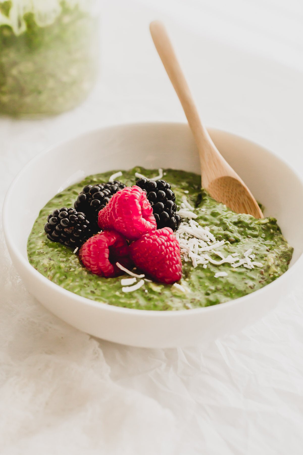 Matcha overnight oats in a white bowl with wooden spoon.