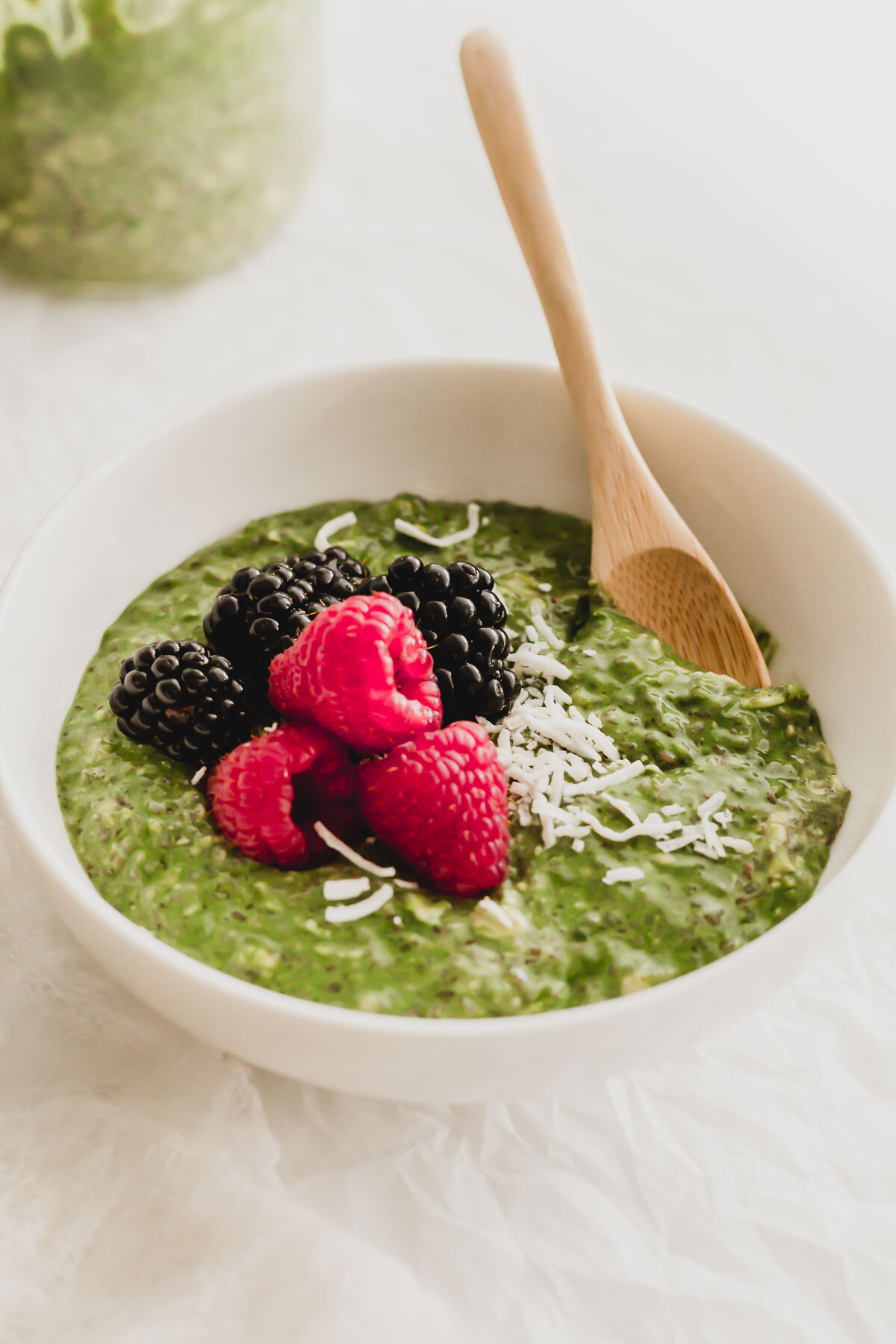Matcha overnight oats in a white bowl with wooden spoon.
