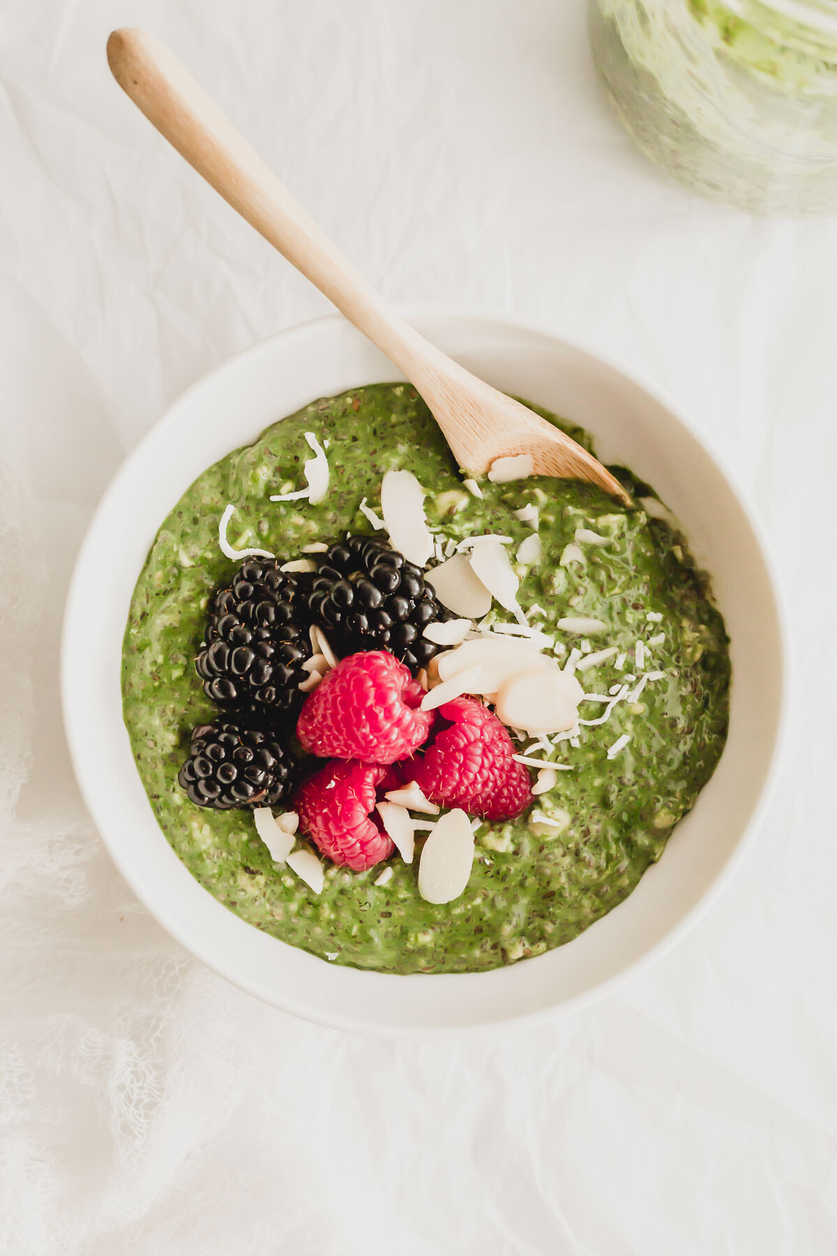 Matcha overnight oats in a white bowl with wooden spoon.