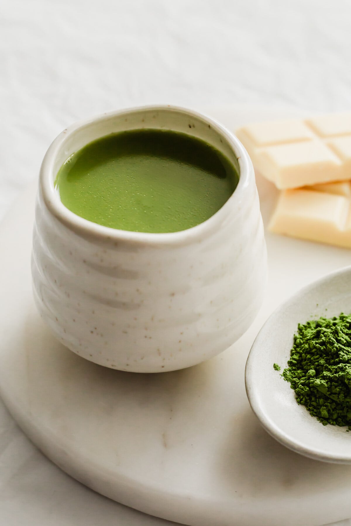 A close up of matcha white hot chocolate in a white ceramic mug.