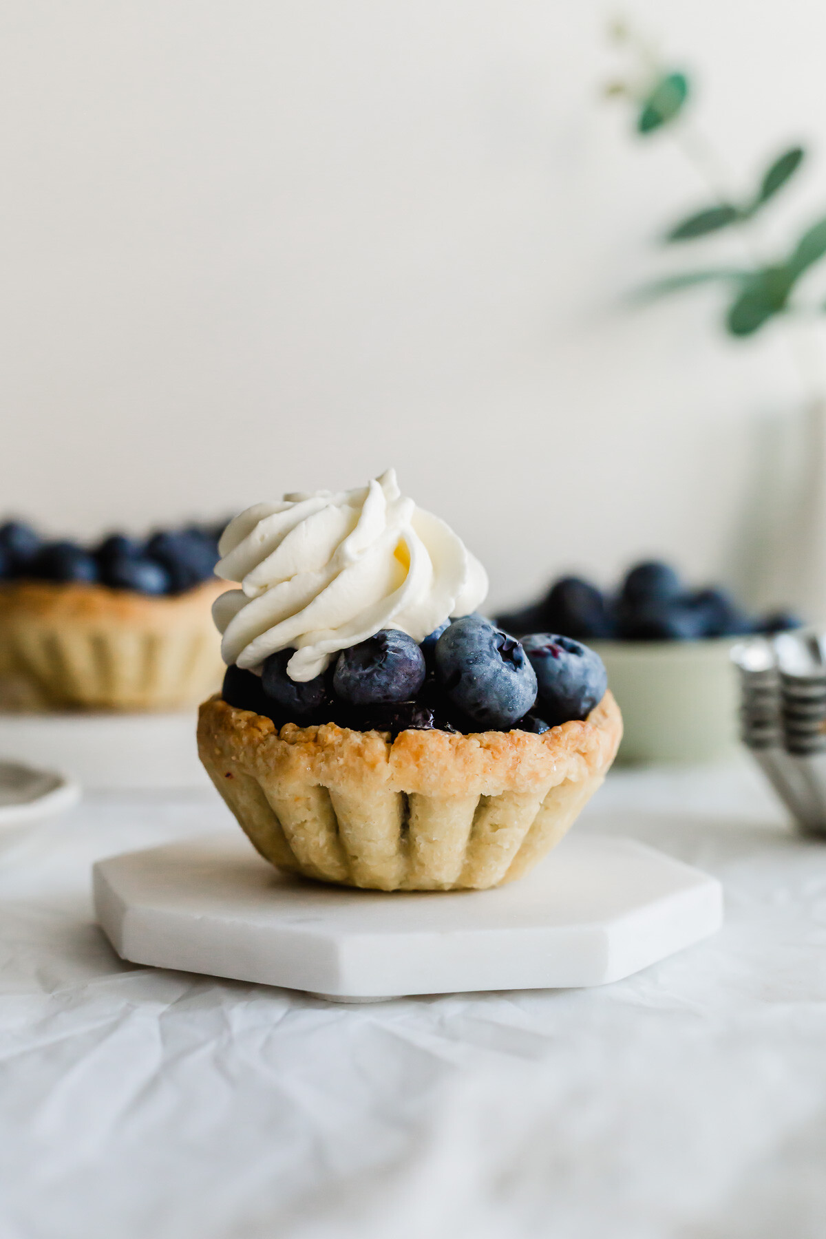 Mini blueberry tart on a white hexagonal coaster.