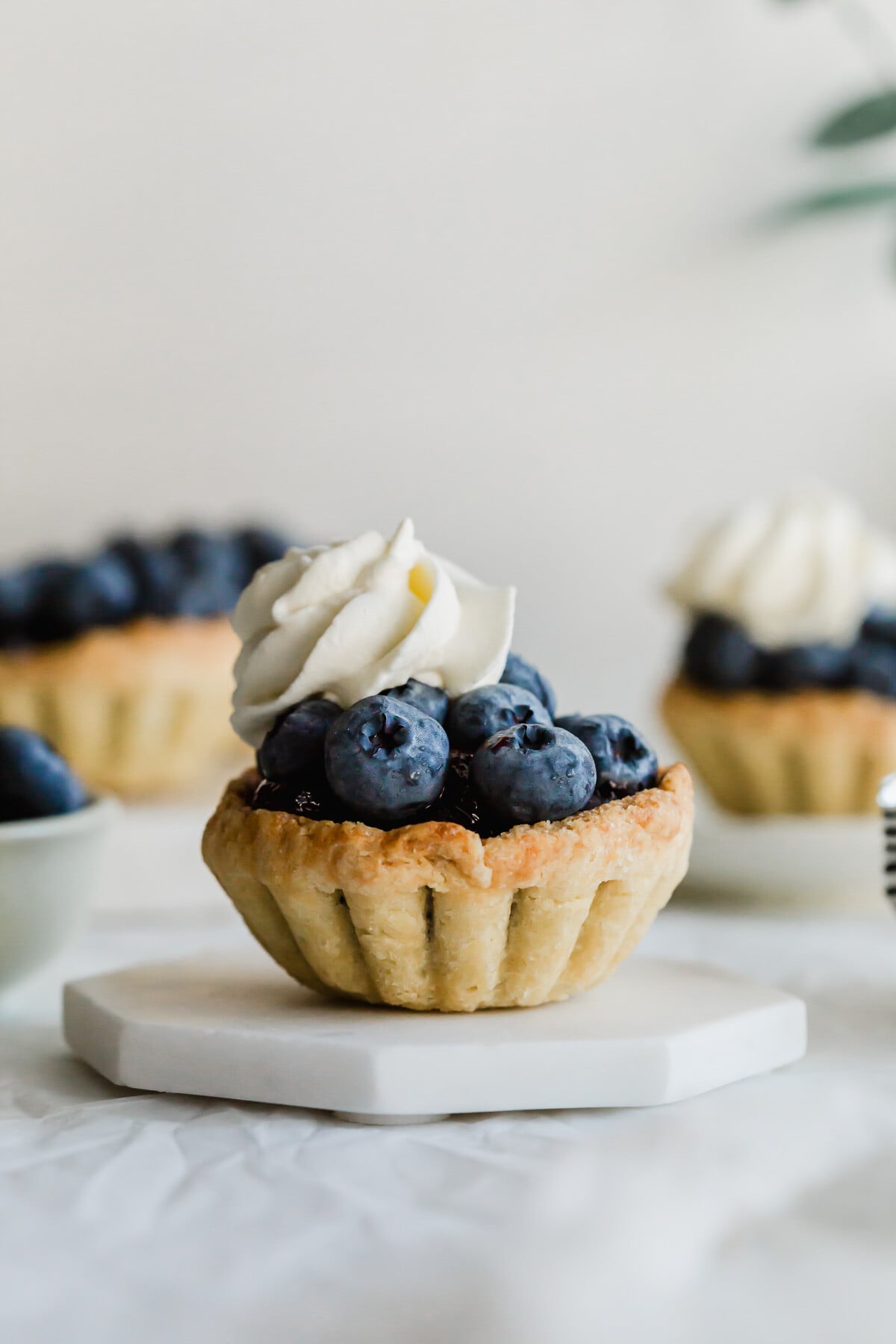 Mini blueberry tart on a white hexagonal coaster.