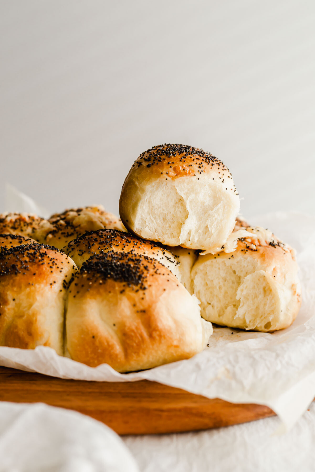 Dinner rolls piled on a wooden board.