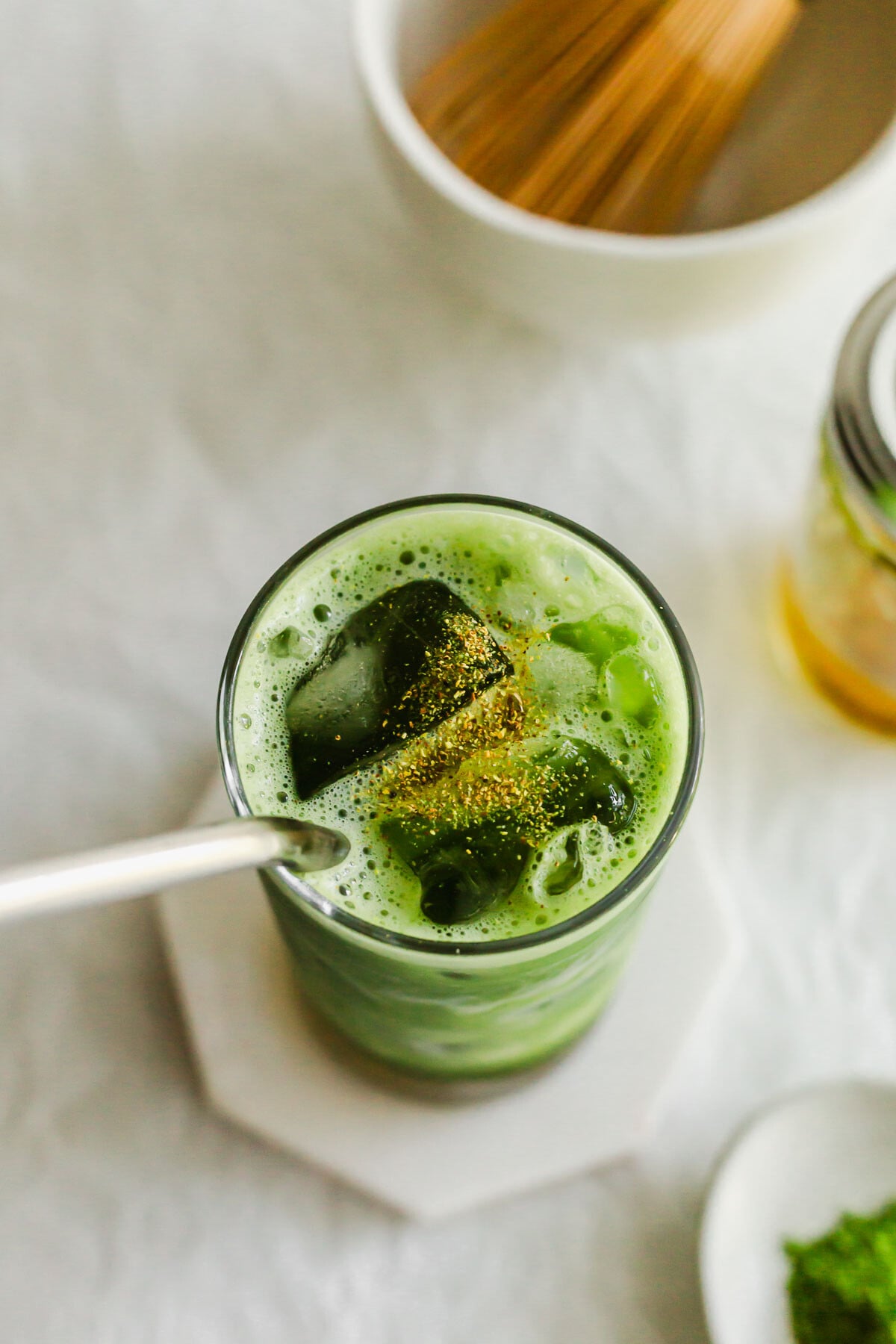 Matcha osmanthus tea in a tall glass with straw.