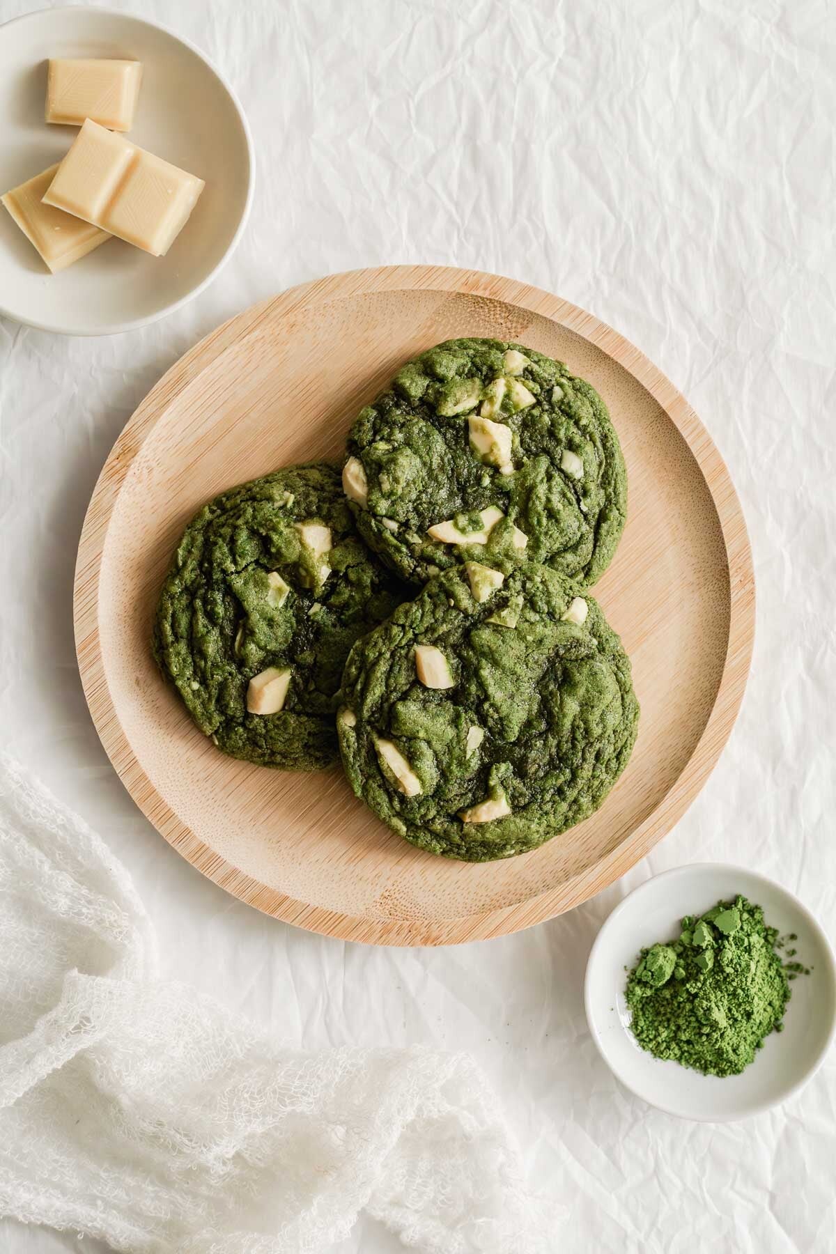 Matcha white chocolate chunk cookies on a wooden round plate.