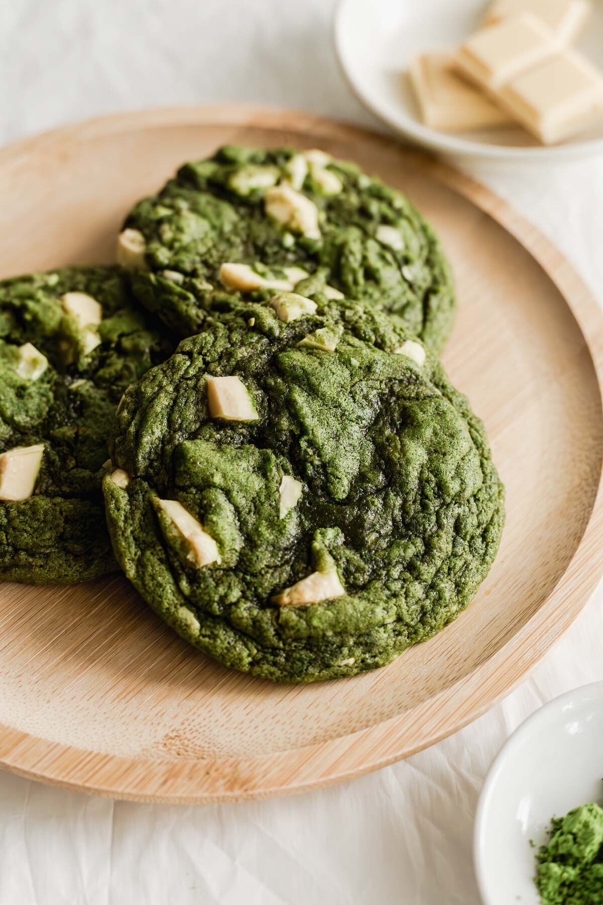 Matcha white chocolate chunk cookies on a wooden round plate.