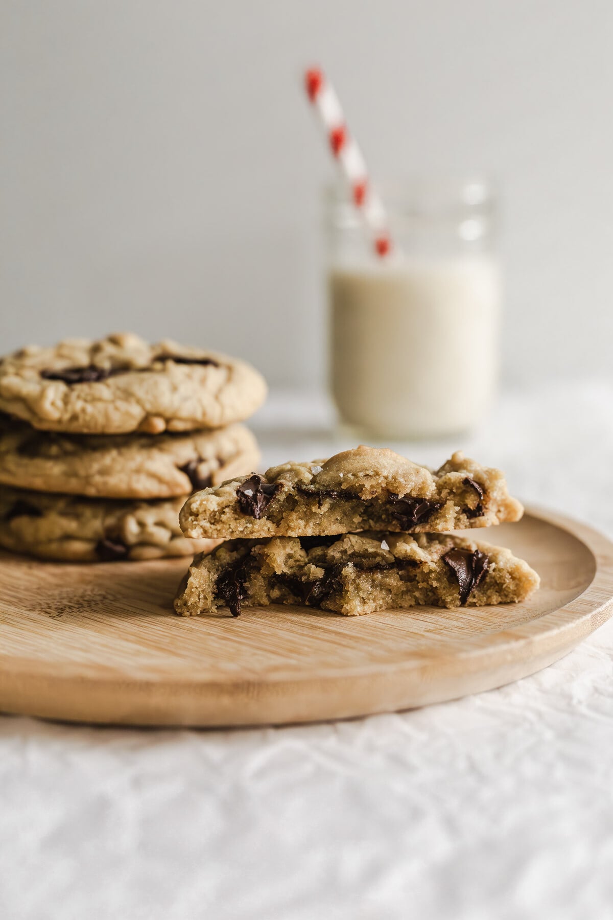 Chocolate chip cookies ripped in half on a wooden plate.