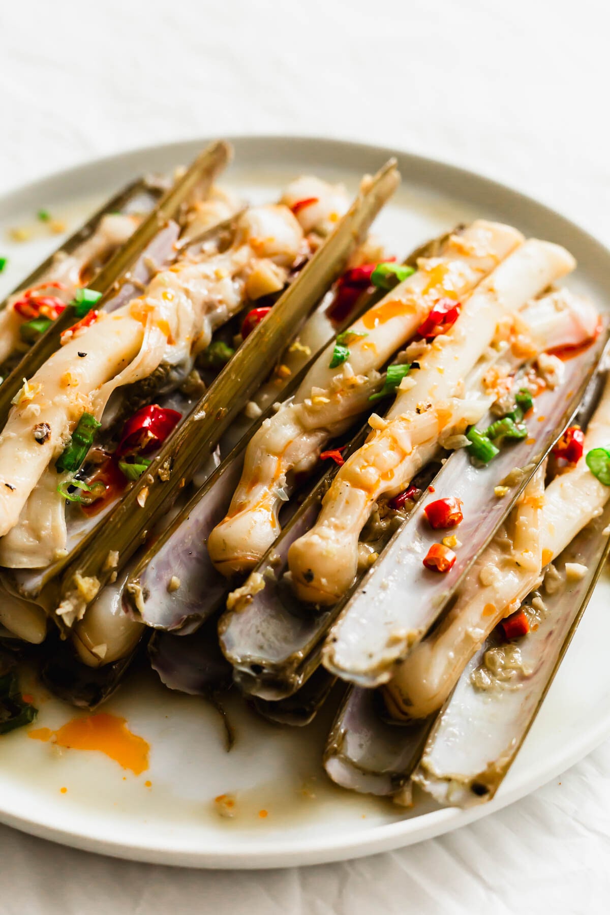 Cooked Chinese razor clams on a white dish.