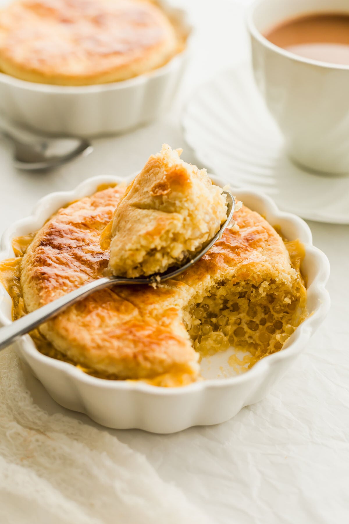 Baked tapioca pudding in a white ramekin, with a spoonful on top.