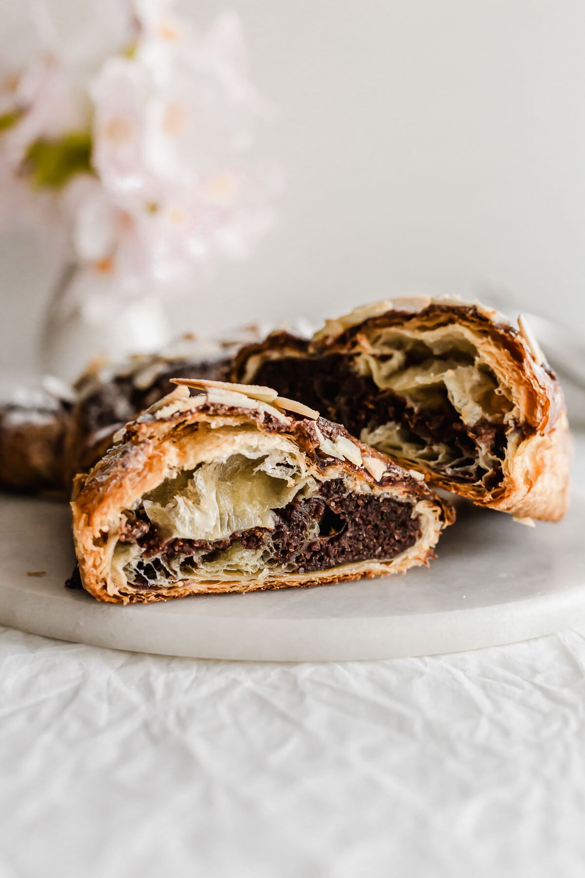 Cut open chocolate almond croissants on a marble round.
