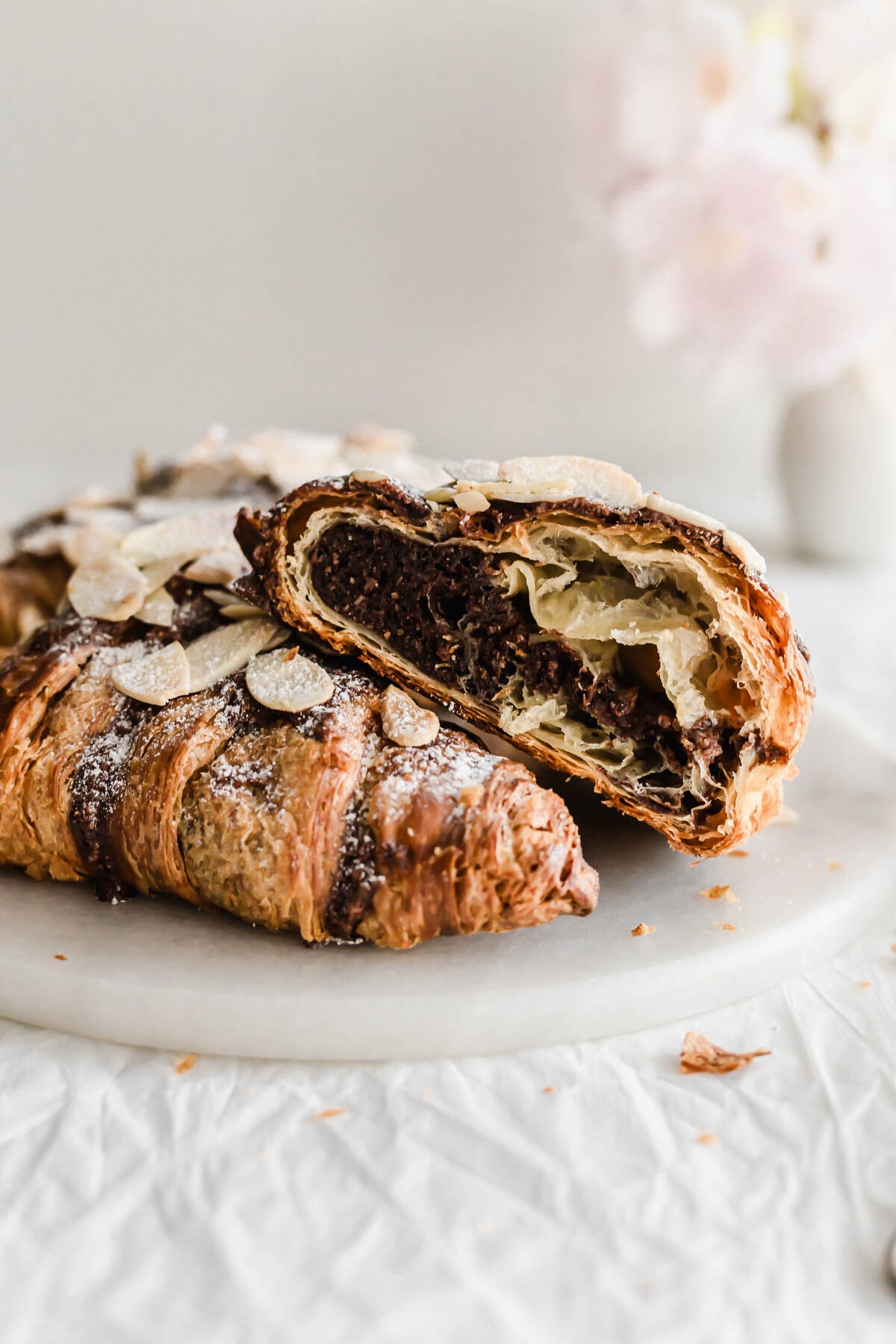 Cut open chocolate almond croissants on a marble round.