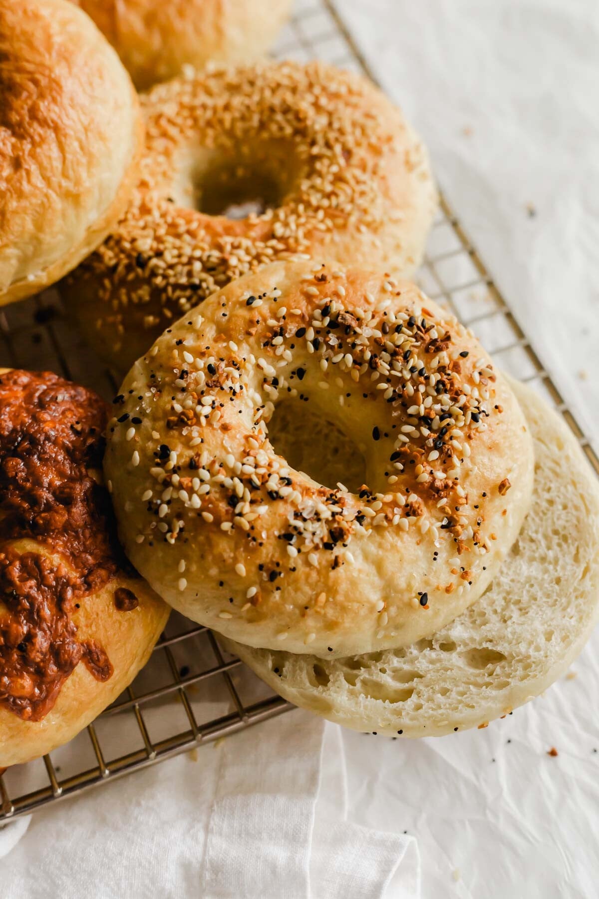 Sliced homemade bagel on wire rack.